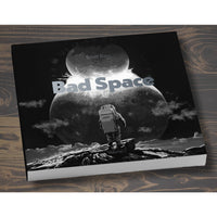 Book titled 'Bad Space' with an astronaut on a moon surface design on a wooden surface