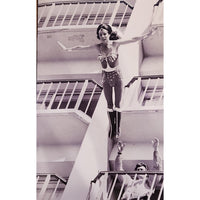 Black and white photo of a woman hanging from a balcony with people below.